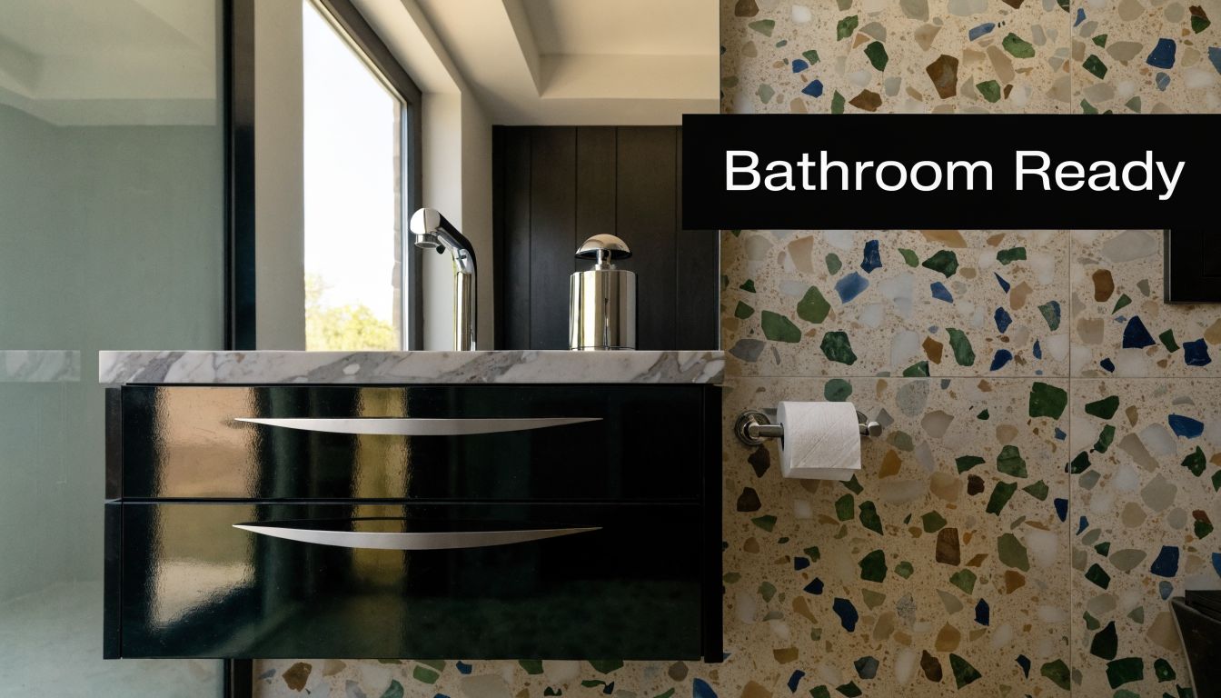 A modern bathroom vanity featuring black cabinets, a marble countertop, and colorful terrazzo style wall tiles.