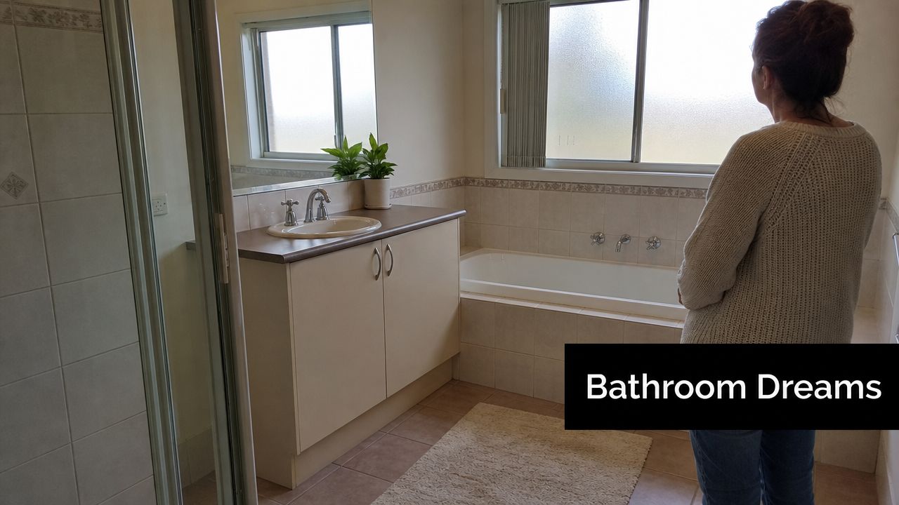 A woman stands in a bright, tiled bathroom considering potential renovation ideas for the space.