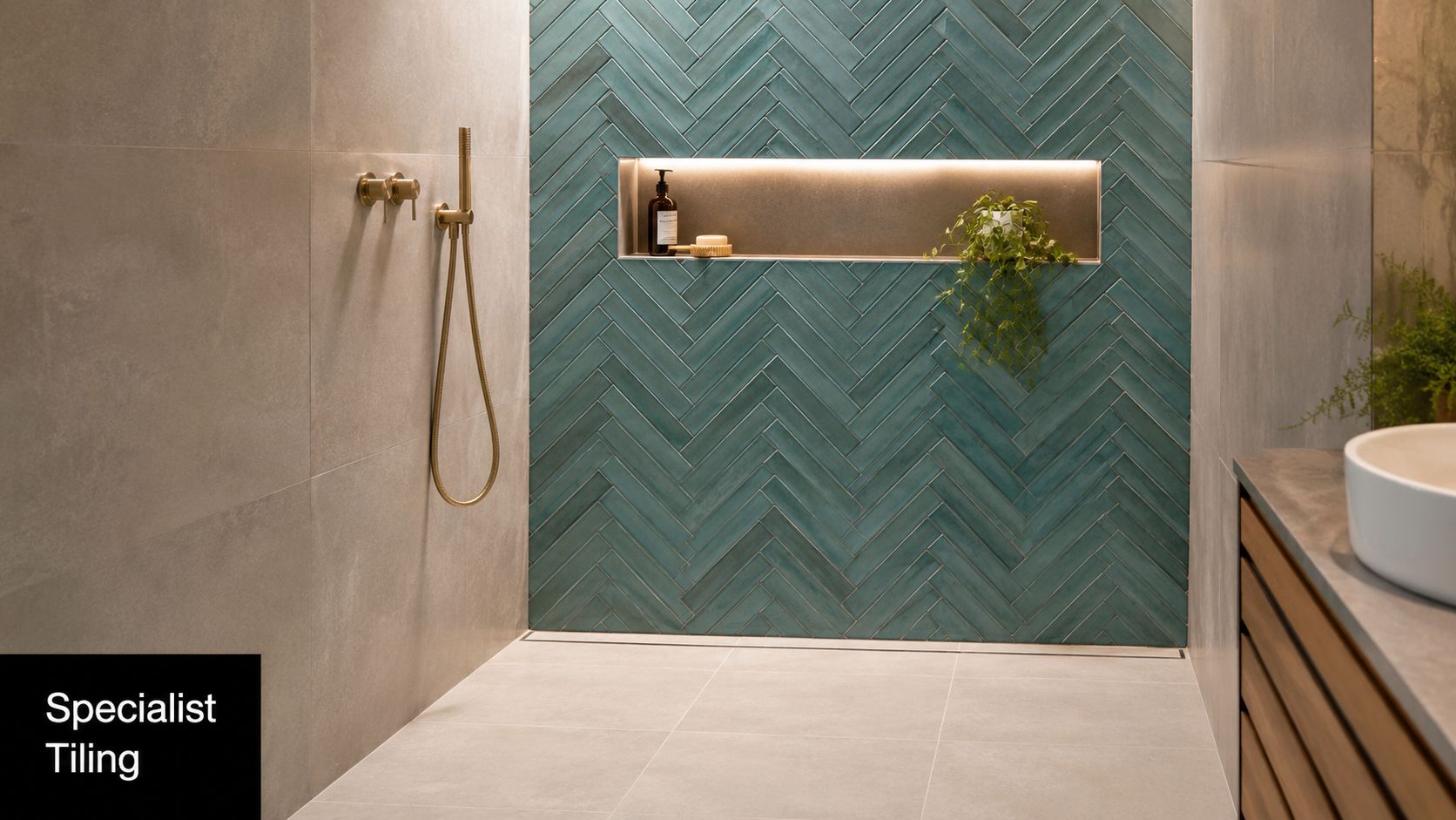 A modern bathroom shower area featuring blue herringbone tiles and a recessed shelf with gold fixtures.