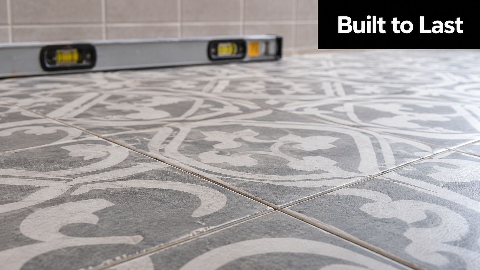 Close up view of patterned grey and white bathroom floor tiles with a spirit level tool.